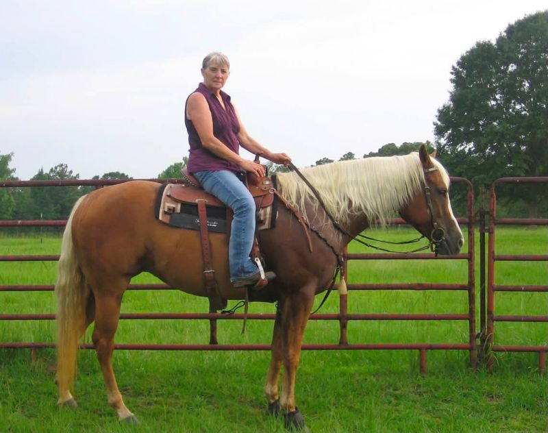 Merrill G. Frost, the matriarch of 4F, riding a palomino Quarter Horse by a pasture fence