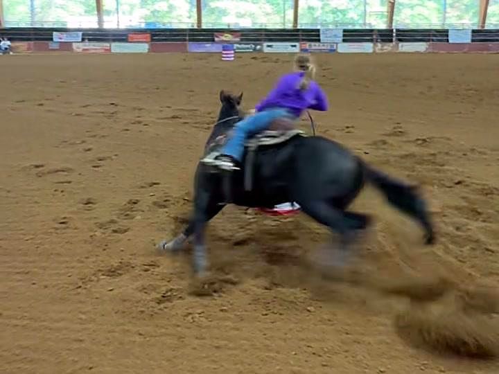 Adeline Frost and Blackie, a black horse, digging around a barrel with dirt flying