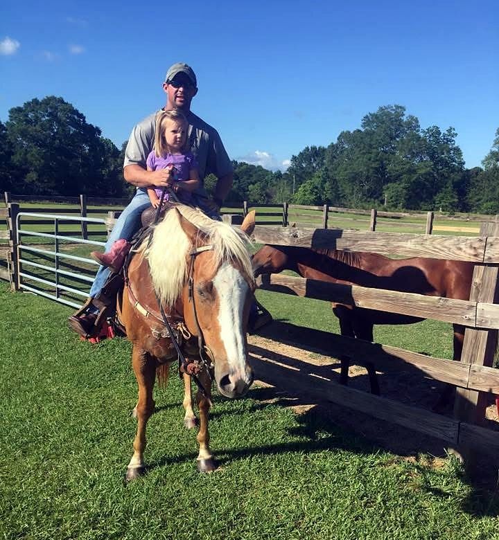 A very young Adeline Frost in a purple shirt riding double with her dad on Sassy, a palomino, at the farm